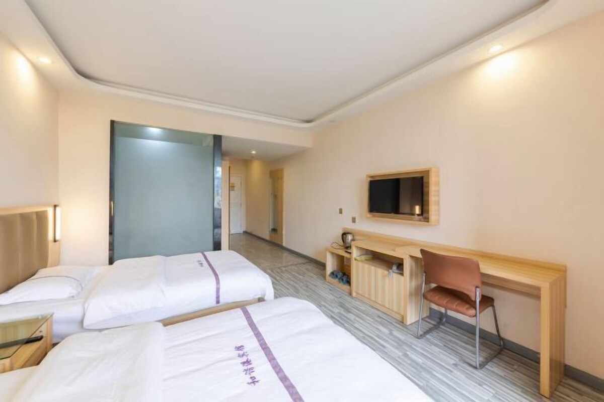A hotel room with two beds, a desk, a chair, a television, and a small cabinet.