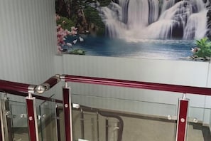 A staircase with a glass railing and a waterfall mural in the background. - Harmony Harbour Hotel (Sixin Avenue Subway Station Hancheng Garden ) (Wuhan)
