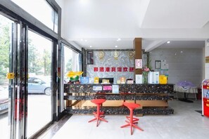 A reception area with a marble counter, red stools, a glass door, and a view of the street. - Harmony Harbour Hotel (Sixin Avenue Subway Station Hancheng Garden ) (Wuhan)