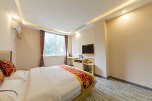 A hotel room with a bed, a desk, a television, and a window.