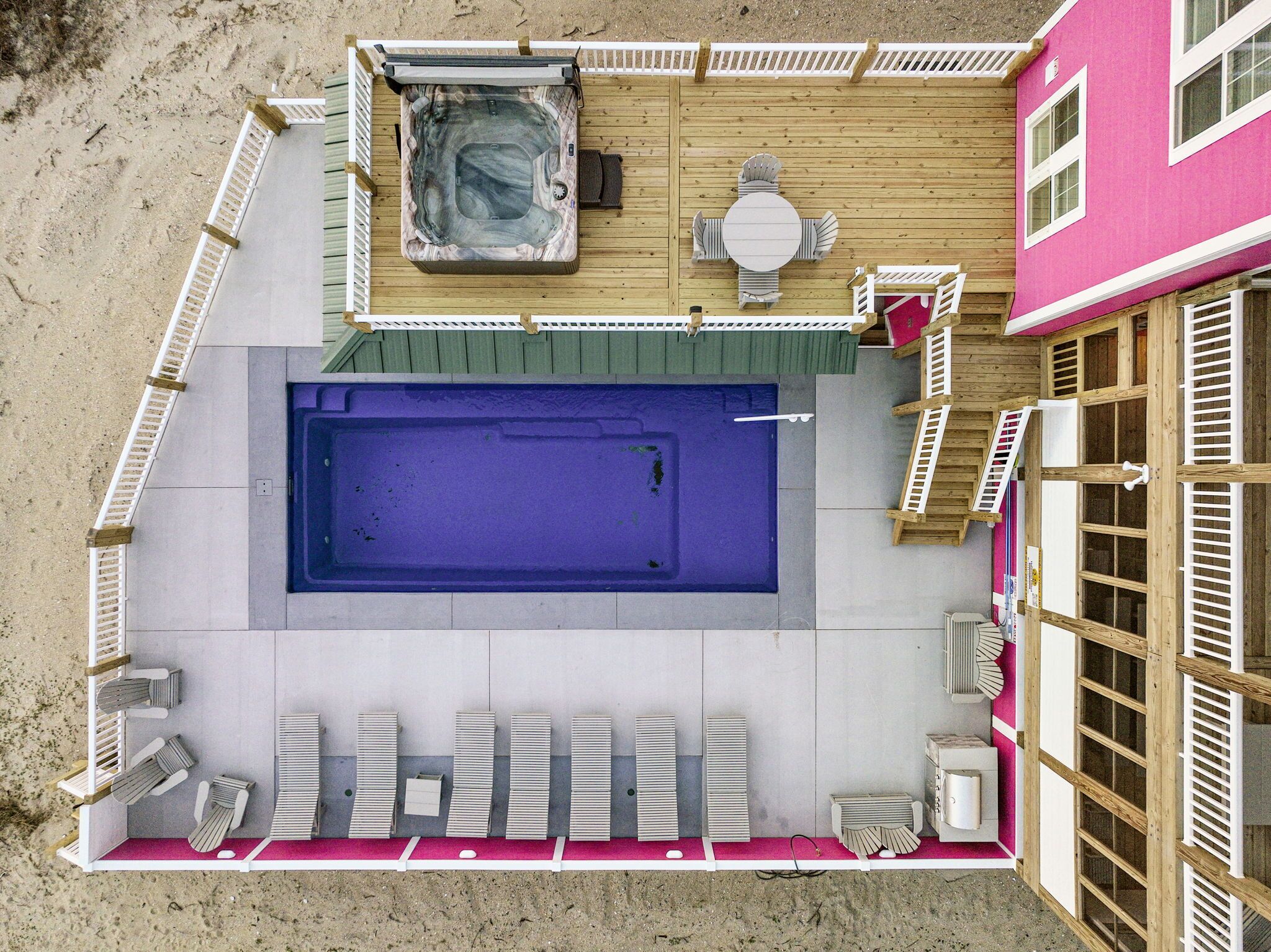 A rooftop pool area with a hot tub, lounge chairs, and a table.