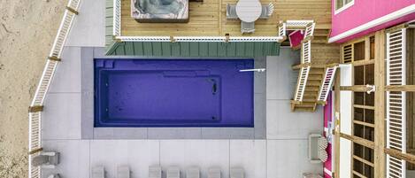 A rooftop pool area with a hot tub, lounge chairs, and a table.