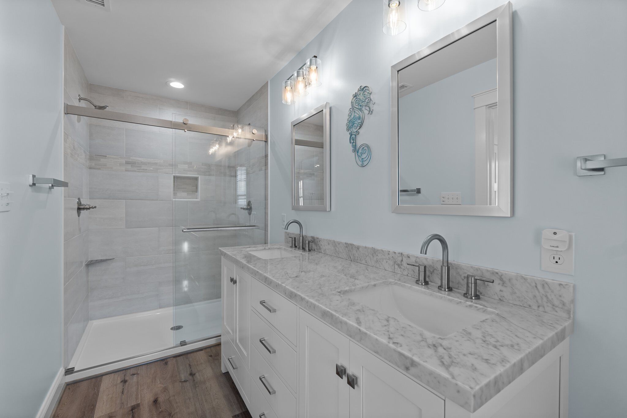 A modern bathroom with a glass shower enclosure, a double sink vanity, and a large mirror.