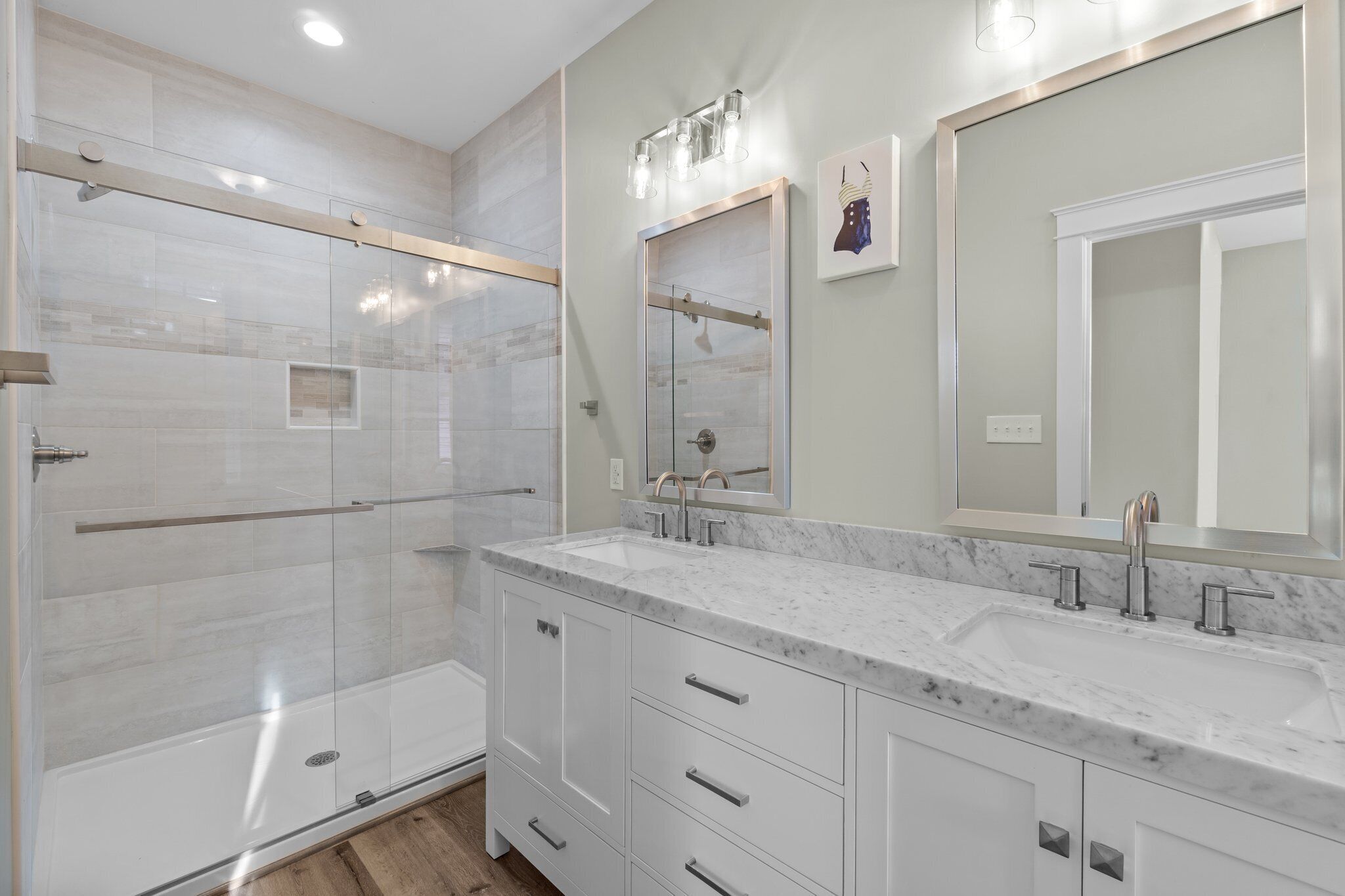 A modern bathroom with a glass shower enclosure, a double sink vanity, and a large mirror.