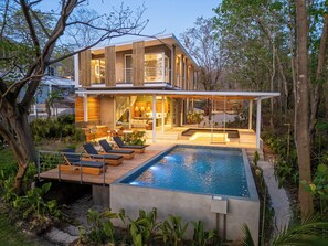 A modern house with a swimming pool, outdoor seating, and a well-maintained garden. - Brand New House with Pool, Walk to Beach (Playa Grande)