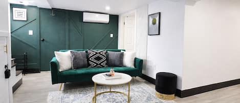Un salon moderne avec un canapé vert, une table basse ronde et un tapis à motifs.