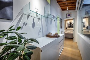 A modern interior with a white counter, glass shelves, a chessboard, and a plant. - YiD luxury & Design penthouse L5 (Firenze)