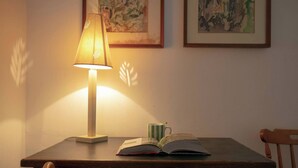 Un escritorio de madera con una lámpara, un libro abierto y una taza a rayas.