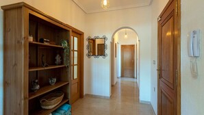 Un pasillo con estanterías de madera, un espejo y una puerta.