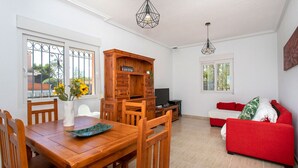 Un comedor con una mesa y sillas de madera, un armario de madera y un sofá rojo.