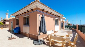 Una terraza en la azotea con un área de estar techada, un pérgola y vistas del horizonte de la ciudad.