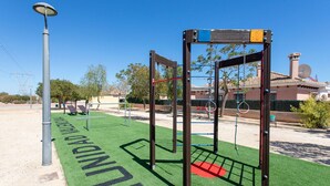 Un parque infantil con una estructura para escalar y una farola solar.
