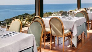 A restaurant with tables set for dining, overlooking a scenic view of the ocean. - Two-room apartment of approximately 42 m2 with air conditioning composed of a living room with TV, foldaway bed and single sofa bed, kitchenette equipped with electric hobs and fridge.Bedroom with double bed, bathroom with shower and hairdryer, shaded ve (Teulada)