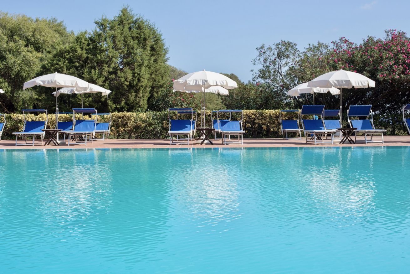 A swimming pool with blue lounge chairs and white umbrellas.