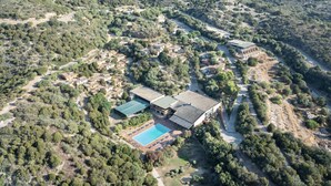 An aerial view of a resort with multiple buildings, a swimming pool, and surrounding greenery.