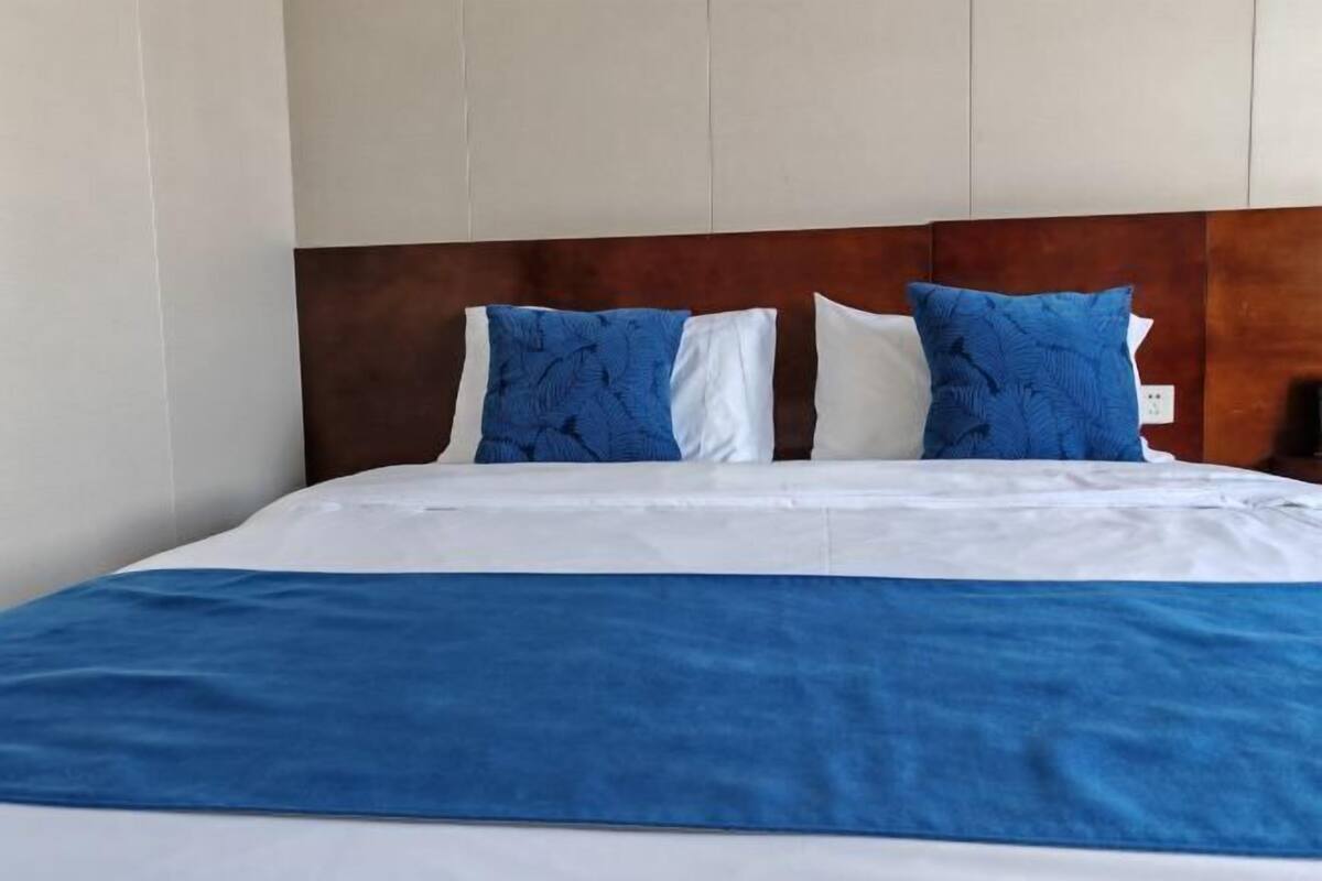 A bed with a wooden headboard, white and blue bedding, and two blue pillows.