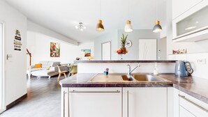 A modern kitchen with a marble countertop, stainless steel sink, and pendant lights.