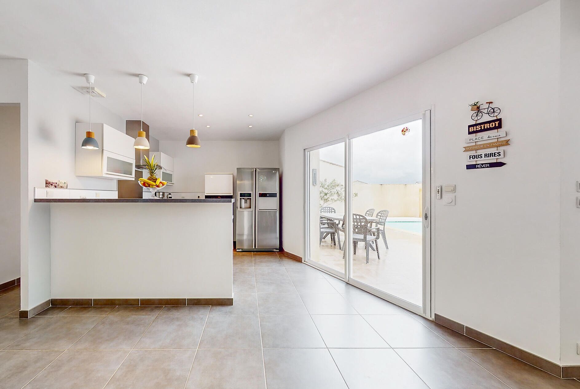Een moderne keuken met een centraal eiland, roestvrijstalen apparatuur en hanglampen.