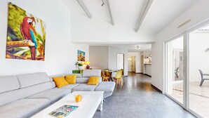 A modern living room with a grey sofa, yellow cushions, a coffee table with a magazine, and a painting of a parrot.
