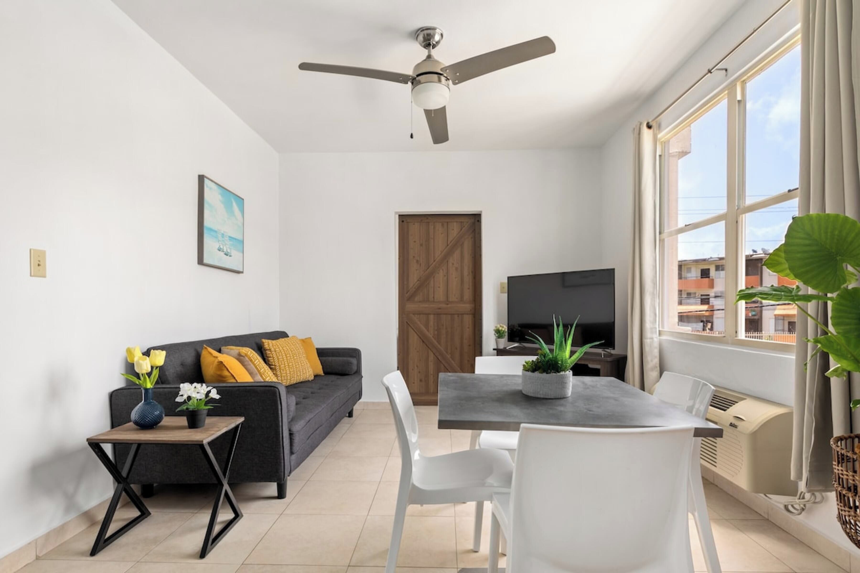 A modern living room with a sofa, TV, dining table, and chairs.