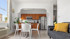 Una cocina moderna con armarios de madera, un refrigerador de acero inoxidable y una zona de comedor con sillas blancas.
