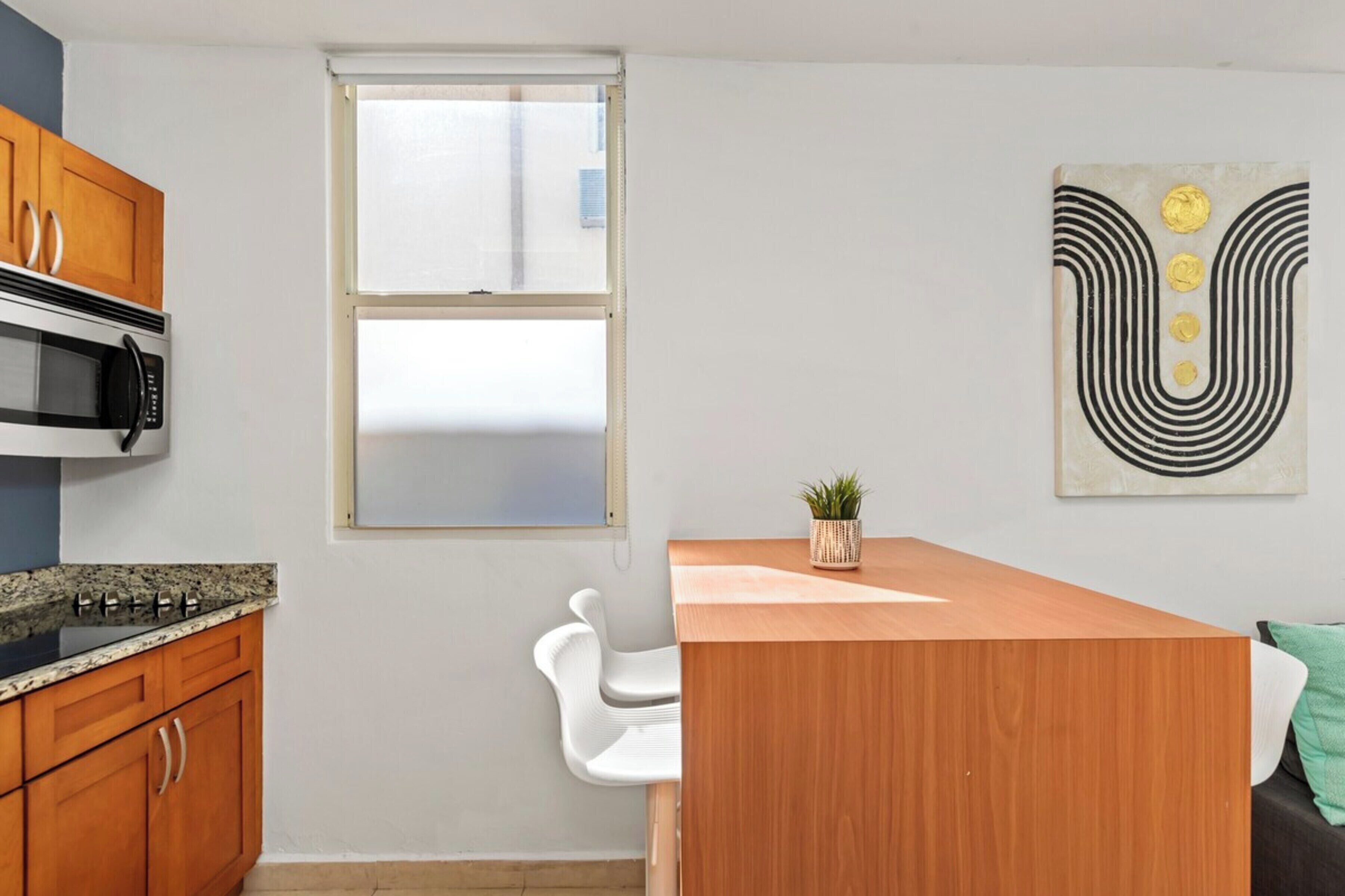 A modern kitchen with wooden cabinets, a microwave, and a window.