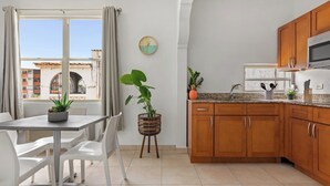 Una cocina moderna con armarios de madera, encimera de granito y un comedor con sillas blancas.