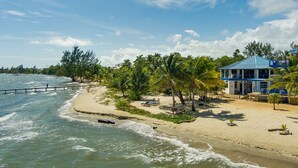 Ein Strand mit einem Haus, Palmen und einem Steg.