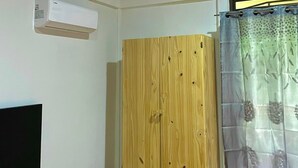 A room with a wooden wardrobe, an air conditioning unit, a curtain, and a black TV stand. - Cabañas El Bosque del Arenal (Peñas Blancas)