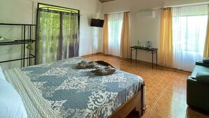A spacious room with a large bed, wooden ceiling, and a television on the wall. - Cabañas El Bosque del Arenal (Peñas Blancas)