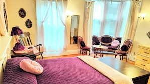 Ein Schlafzimmer mit einem großen Bett, einem Schreibtisch, zwei Stühlen, einem Schminktisch und einem Spiegel.