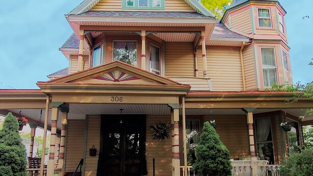 Ein großes, zweistöckiges Haus mit einer auffälligen Veranda und einem turmartigen Anbau auf der rechten Seite.