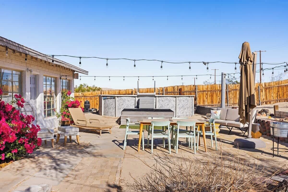An outdoor patio with a barbecue area, seating, and string lights.