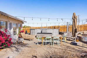 An outdoor patio with a barbecue area, seating, and string lights.