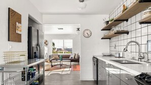 A modern kitchen with a central island, built-in appliances, and a view to the outside. - Casa Homestead Hemel| Pool | Downtown 29 Palms (Twentynine Palms)