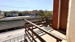 Ein Balkon mit Blick auf eine Wohngegend, einen Zaun und ein Gebäude mit heruntergelassener Rolltreppe.