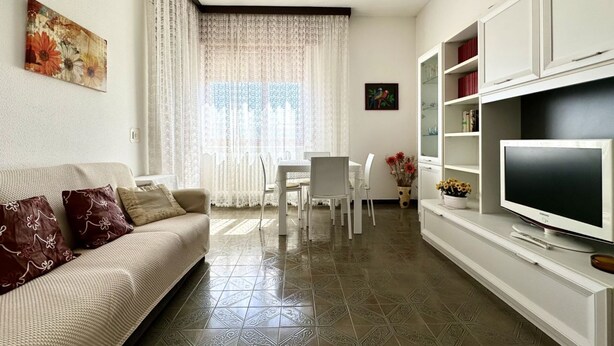 Ein Wohnzimmer mit Sofa, Fernseher und Essbereich.