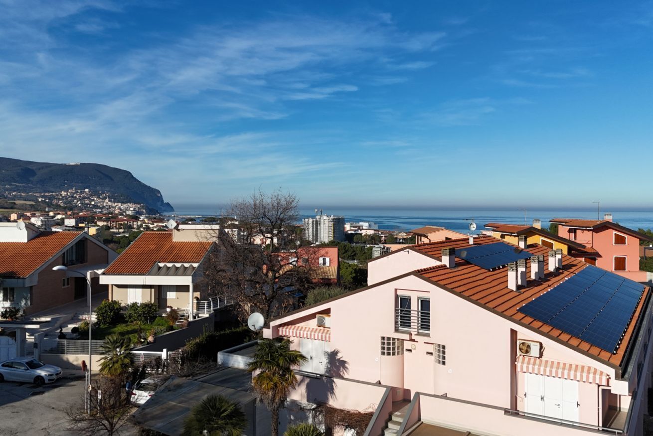 Una zona residencial costera con casas, cielo despejado y vista al mar.