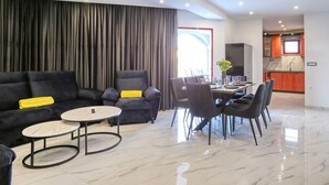 Una sala de estar moderna con un sofá, sillas, una mesa de comedor y una zona de cocina.