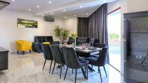 Un comedor moderno con suelo de mármol, sillas negras y amarillas, una mesa de comedor para seis personas y un ventanal con cortinas.