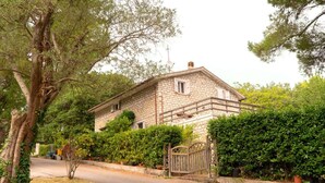 A stone house with a gated entrance, surrounded by trees and shrubs. - S339 - Sirolo, wonderful three-room apartment surrounded by nature (Sirolo)