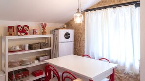 A compact kitchen with a white table, red chairs, a hanging light fixture, and a stone wall. - S339 - Sirolo, wonderful three-room apartment surrounded by nature (Sirolo)