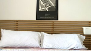 A bed with white pillows and a colorful quilt, a wooden headboard, and a framed picture of a cat on a chair. - Palme 4 - Marcelli, one-room apartment on the ground floor, Residence Le Palme (Marcelli)