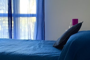 A bed with a blue bedspread, a pillow, and a purple book on a bedside table. - Palme 5 - Marcelli, one-room apartment on the ground floor, Residence Le Palme (Marcelli)