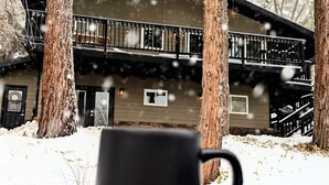 Une cabane dotée d’un balcon, entourée de neige et d’arbres.