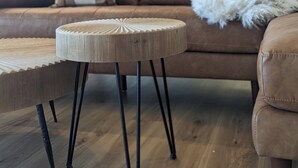Un salon moderne avec un canapé marron, une table basse ronde en bois et un plaid blanc.