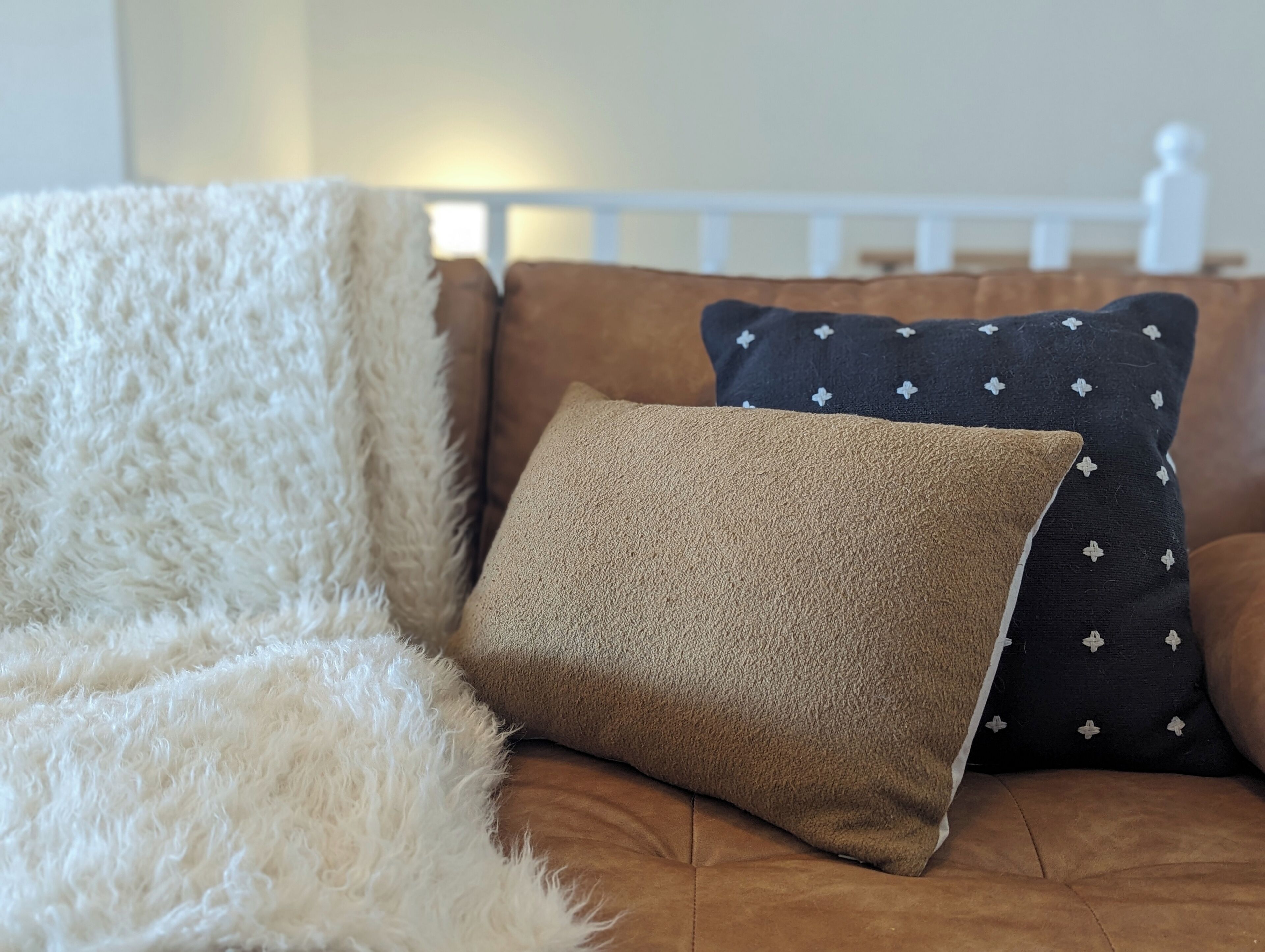 Una cama con un edredón blanco y esponjoso, y dos almohadas, una marrón y otra con diseño de estrellas.