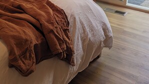 Une chambre à coucher avec un lit, un fauteuil suspendu et une vue sur l’extérieur grâce à une porte vitrée.