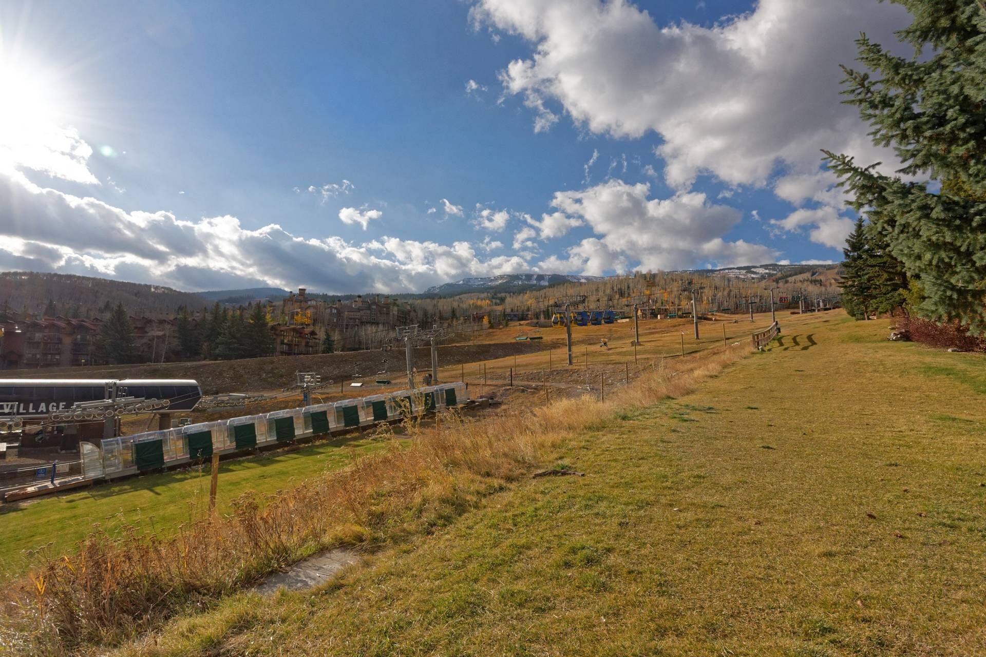 A train station with tracks, a platform, and a mountainous backdrop.