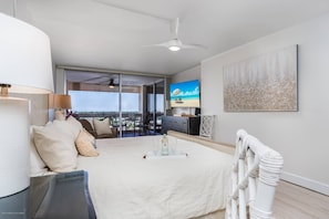 A modern bedroom with a bed, a TV, and a balcony with a view.